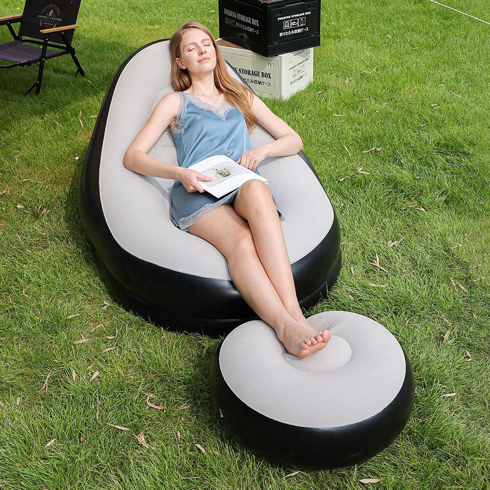Mulher relaxando ao ar livre no sofá inflável, com os pés apoiados no puff